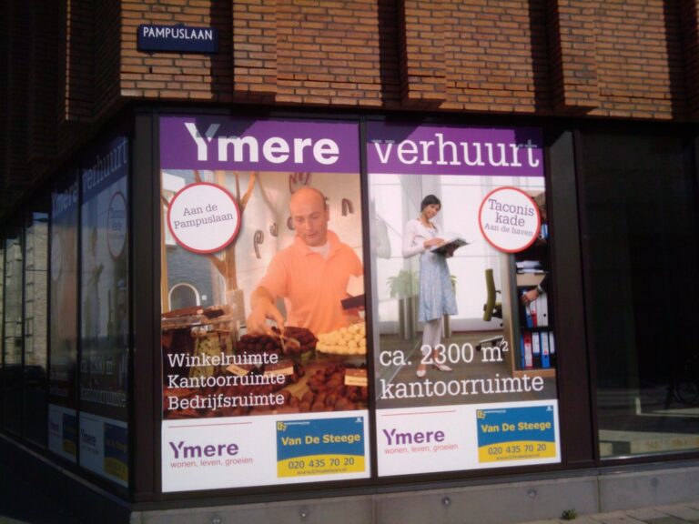 In de etalages van winkels hangen advertenties voor kantoor- en winkelruimtes te huur in Ymere. De linkerposter toont een man die brood schikt, de rechterposter een vrouw met papieren. Borden en contactgegevens zijn zichtbaar.